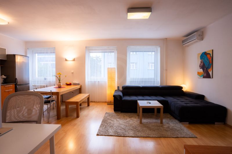 Wohnzimmer einer 4-Zimmer-Wohnung mit Sofa, Esstisch und Holzboden.