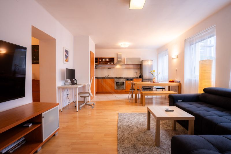 Wohnzimmer mit Küche in einer 4-Zimmer-Wohnung, mit einem Boden in Holzoptik und vielseitiger Einrichtung.