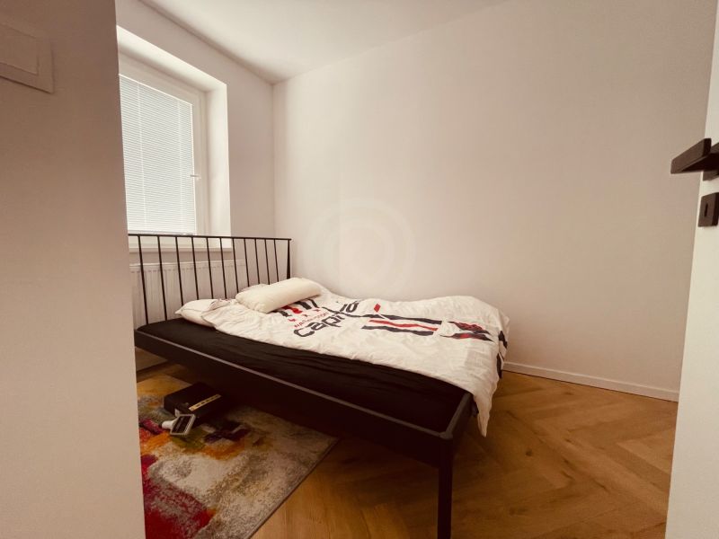 Schlafzimmer mit einem Eisenbett und einem Boden mit Holzdekor in einer 4-Zimmer-Wohnung.