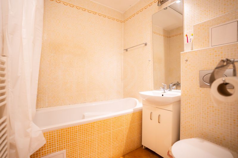 Badezimmer in einer 4-Zimmer-Wohnung mit Badewanne, Waschbecken und Toilette, helle Fliesen.
