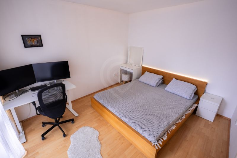 Schlafzimmer mit Bett, Schreibtisch und Boden mit Holzdekor in einer 4-Zimmer-Wohnung.