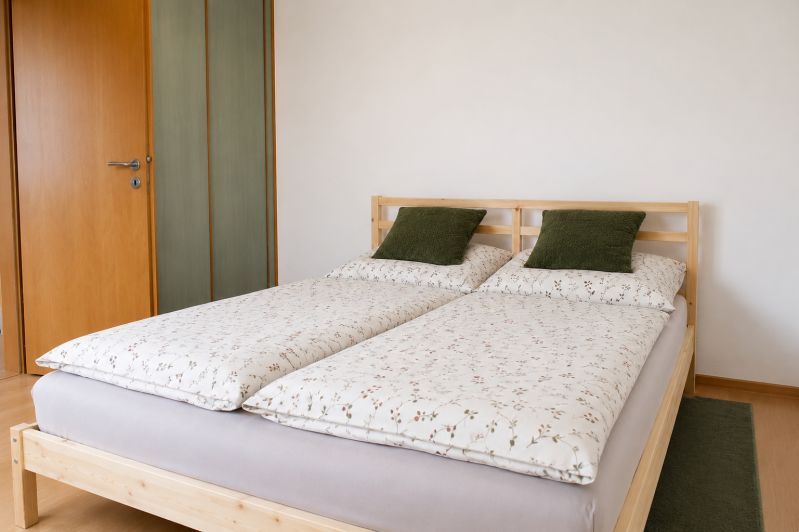 Schlafzimmer mit Doppelbett, Kissen in einer 2-Zimmer-Wohnung auf einem Boden mit Holzdekor.
