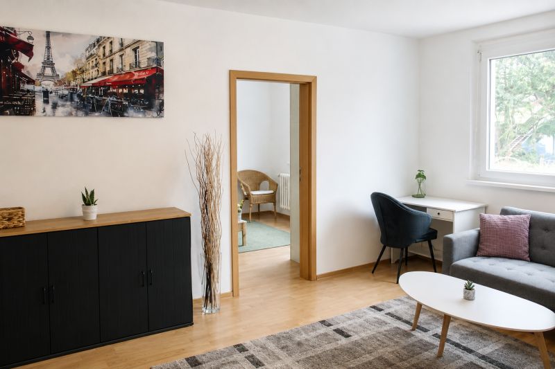 Wohnzimmer in einer 2-Zimmer-Wohnung mit Holzboden und einem Bild von Paris.