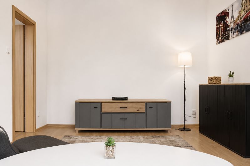 Wohnzimmer mit Holzboden, Möbeln und Stehlampe in einer Zweizimmerwohnung.