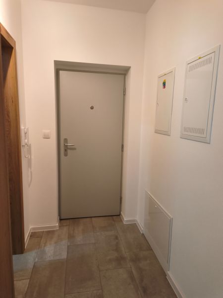 Eingangsflur in einer Einzimmerwohnung mit Fliesenboden und weißen Wänden.