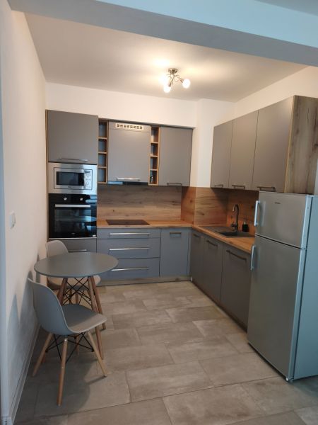 Küche in einer Einzimmerwohnung mit Essecke und grauen Schränken.