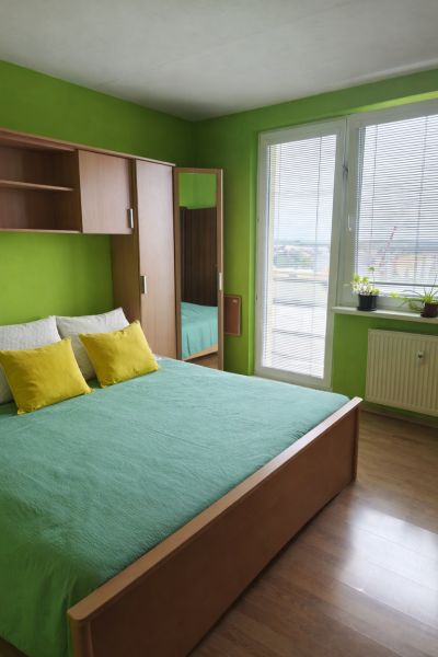Grünes Schlafzimmer mit Bett und Schrank in Holzdekor in einer 3-Zimmer-Wohnung.