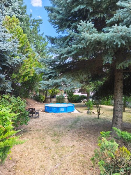 Ein Garten in Mankovce mit einem Pool und einer Bank im Schatten der Bäume neben einem Einfamilienhaus.