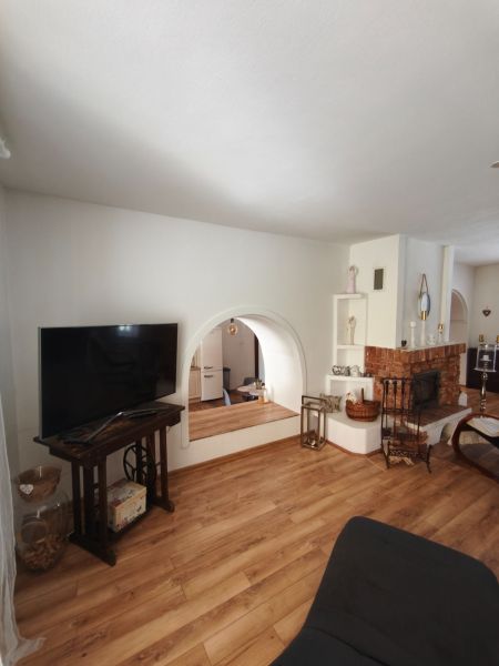 Wohnzimmer mit Kamin in einem Einfamilienhaus, Boden mit Holzdekor, Fernseher auf einem Tisch.