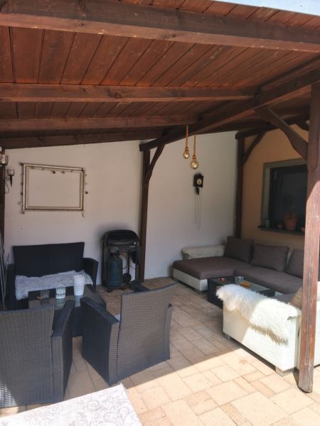 Überdachte Terrasse eines Einfamilienhauses in Mankovce mit Rattanmöbeln und Kamin.