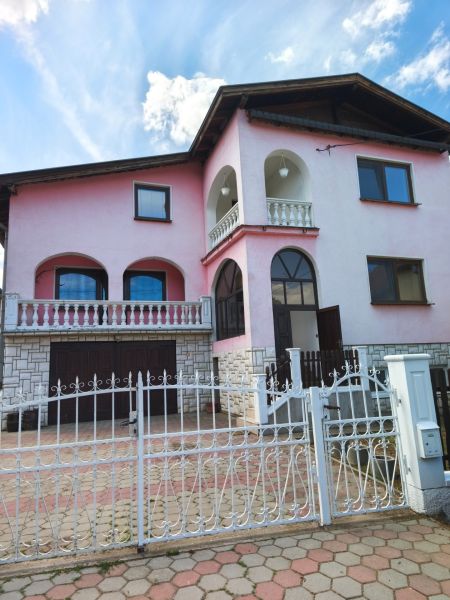 Ein Einfamilienhaus in Mankovce mit rosa Fassade, einem Obergeschoss und einem schmiedeeisernen Zaun.