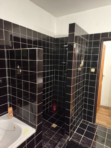 Ein Badezimmer in einem Einfamilienhaus mit schwarzen Fliesen und einer Duschkabine.
