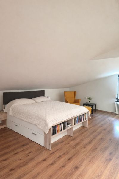 Schlafzimmer in einem Einfamilienhaus mit Holzboden, Bett und Sessel.