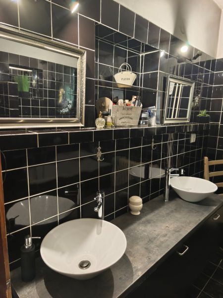 Badezimmer in einem Einfamilienhaus mit schwarzen Fliesen, zwei Waschbecken und Spiegeln.