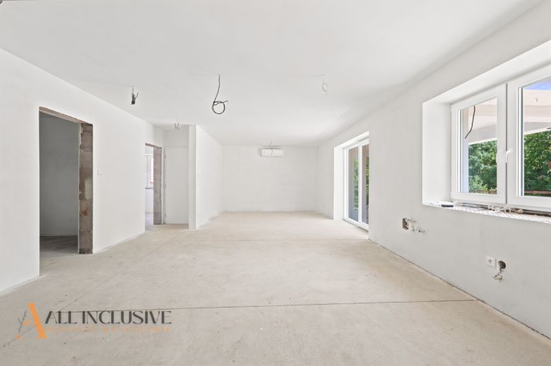 Geräumiges Interieur eines Einfamilienhauses mit weißen Wänden und großen Fenstern.