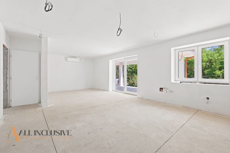 Geräumiges Zimmer in einem Einfamilienhaus mit großen Fenstern und vorbereiteter Beleuchtung.