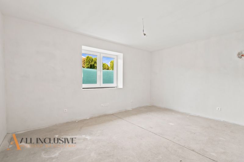 Ein leerer Raum in einem Einfamilienhaus ohne Bodenbelag und mit weißen Wänden.