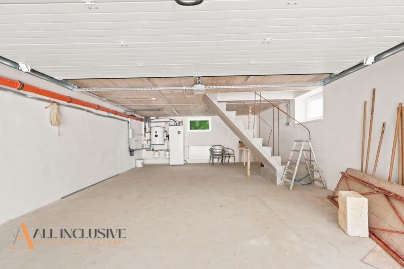 Garage in einem Einfamilienhaus mit Betonboden und Treppen, einfache weiße Wände.
