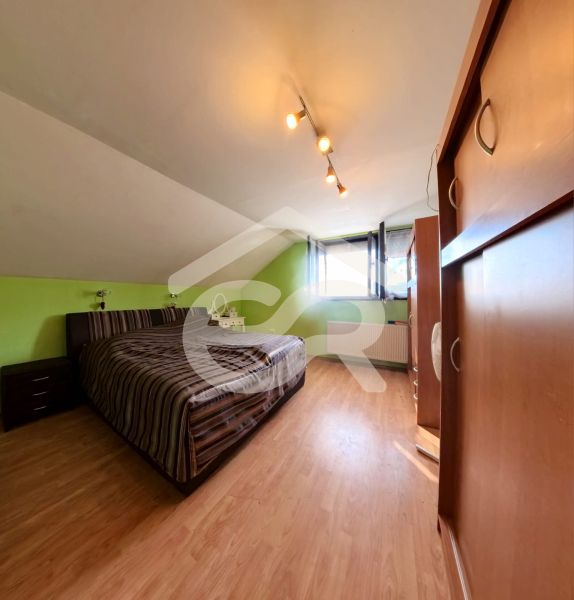 Dachzimmer mit Bett, Schrank und Holzboden in einem Einfamilienhaus.