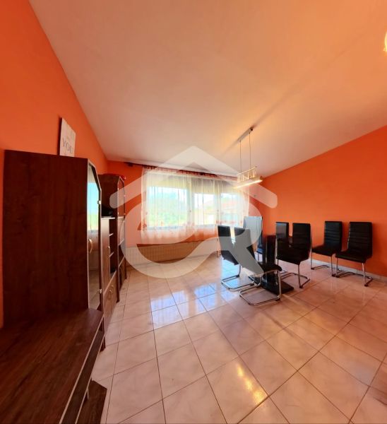 Wohnzimmer in einem Einfamilienhaus mit orangefarbenen Wänden und schwarzen Stühlen.