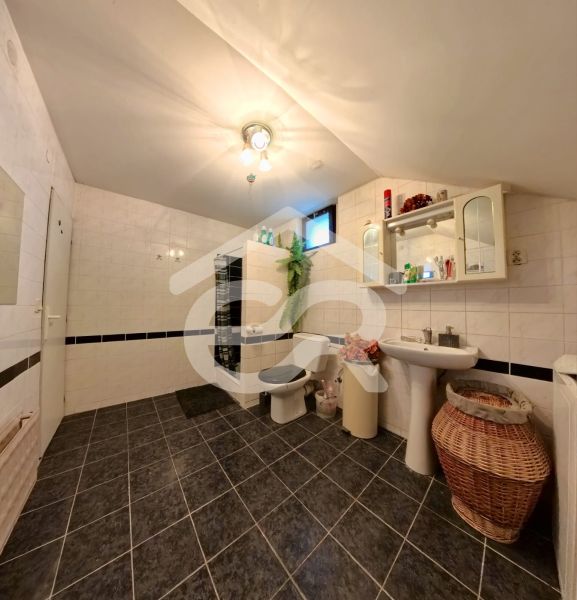Badezimmer mit Fliesen, Waschbecken, Spiegel und WC in einem Einfamilienhaus.