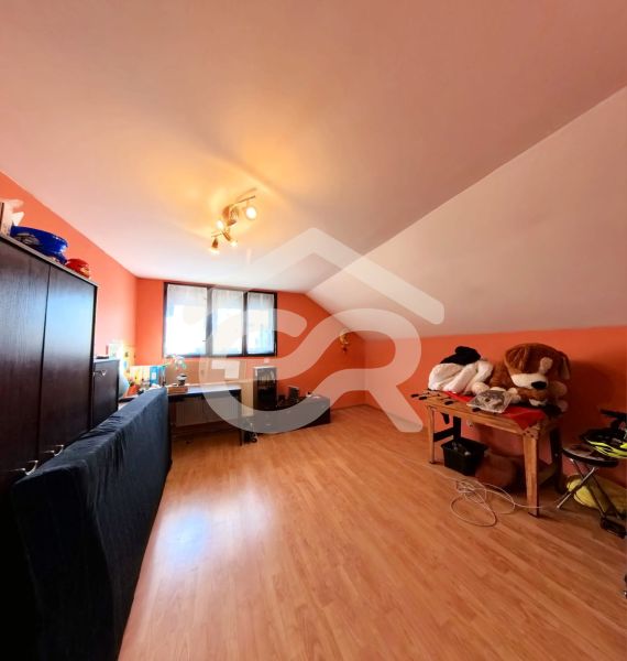 Dachzimmer mit Schreibtisch, Sofa und Holzboden.