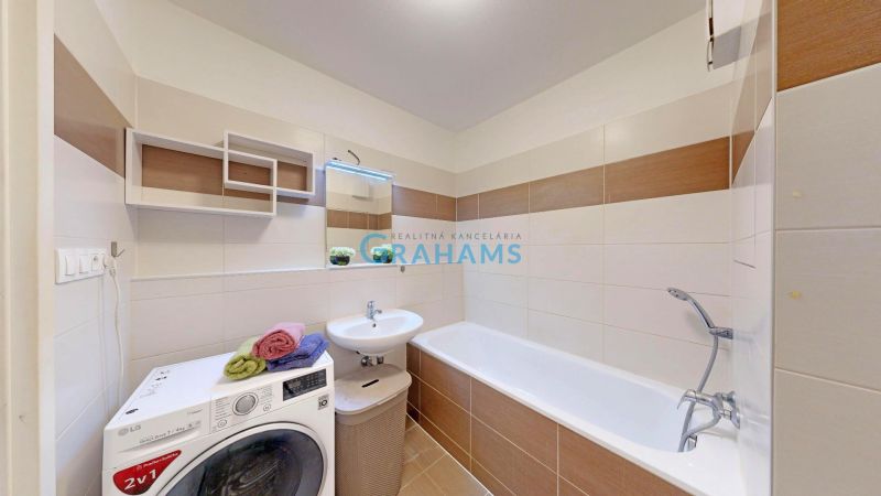 Badezimmer in einer 3-Zimmer-Wohnung mit Badewanne, Waschmaschine und modernem Fliesenbelag.