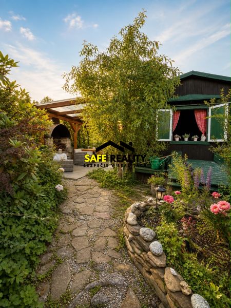 Der Garten bei der Hütte in Žilina mit steinernen Wegen und einem Blumenbeet.