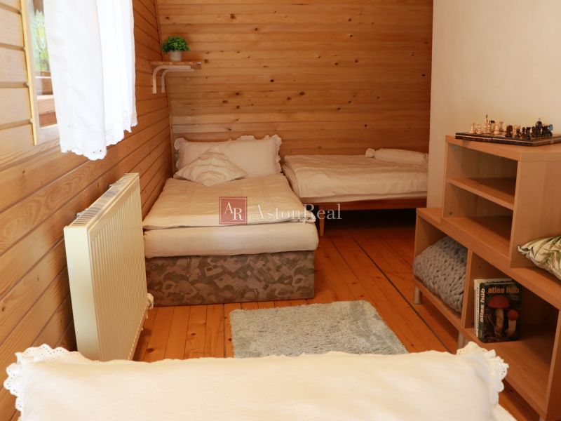 Holzverkleidung im Zimmer einer Hütte, zwei Betten, Boden mit Holzdekor, Bücherregal.