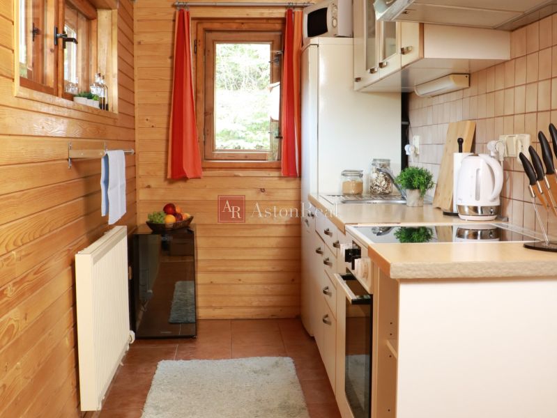 Eine Küche in einer Hütte mit Holzdekor, weißen Geräten und einem Fenster mit Ausblick.