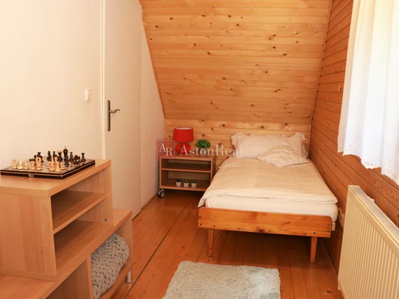 Einzelzimmer mit Holzboden, einem Schachbrett auf dem Tisch und einem Fenster mit weißem Vorhang.