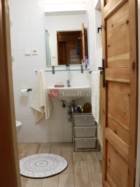 Ein Badezimmer in der Hütte mit Waschbecken, Spiegel und Boden mit Holzdekor.