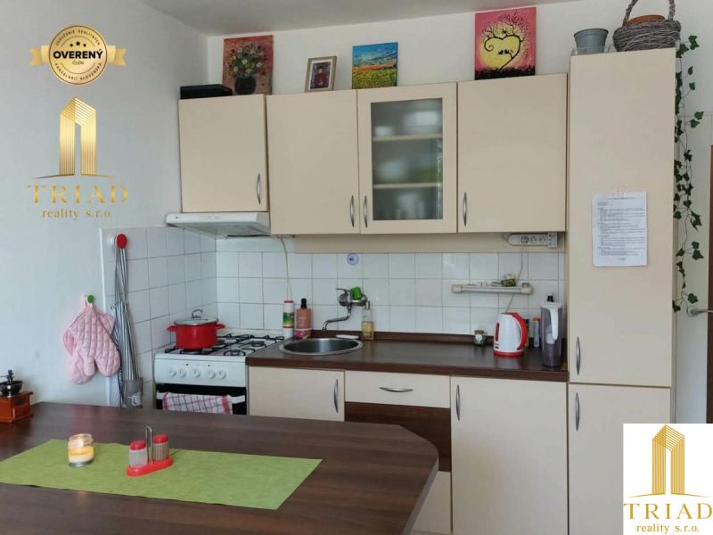 Küche in einer Einzimmerwohnung mit Holzboden und hellen Schränken.