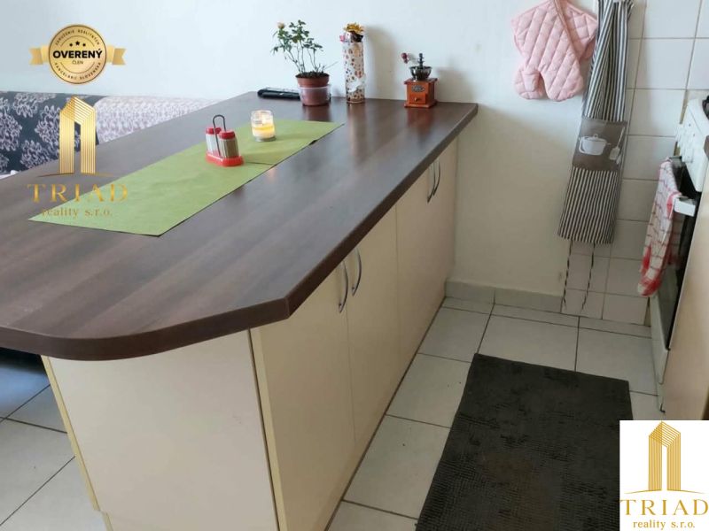Küchenzeile mit Insel in einer Einzimmerwohnung, weiße Fliesen und Dekorationen.