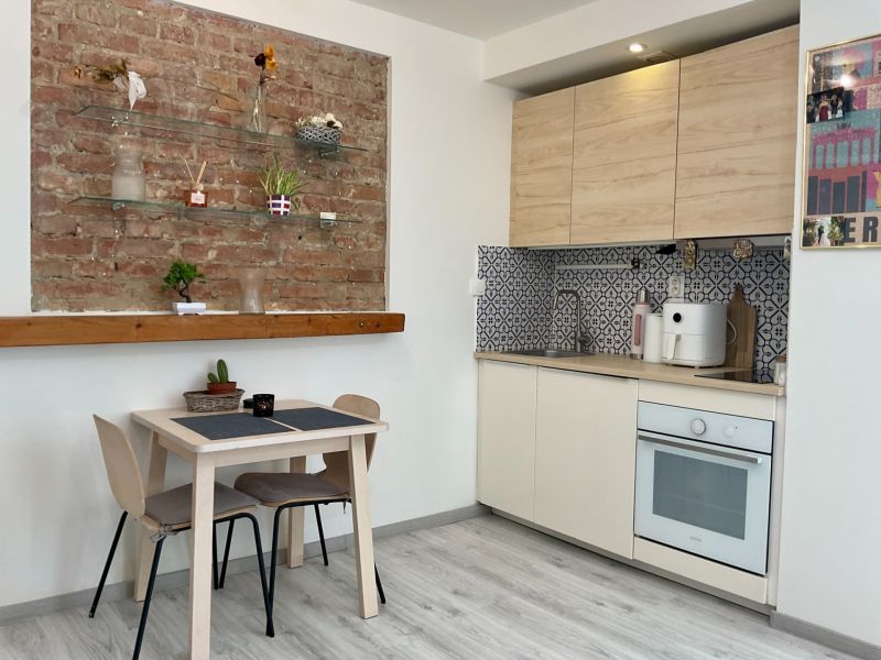 Küchenecke mit einer Ziegelwand und einem Boden in Holzoptik in einer Einzimmerwohnung.