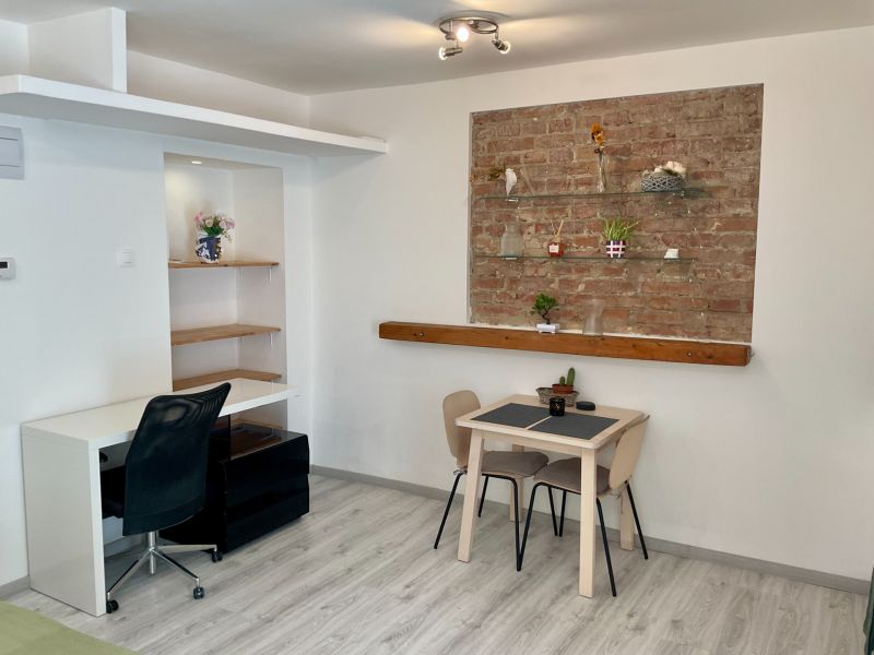 Ein Zimmer mit einer Ziegelwand, einem Tisch und einem Holzboden in einer Einzimmerwohnung.