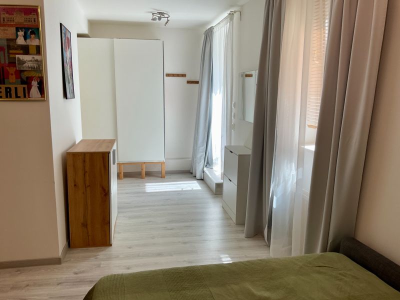 Helles Zimmer mit Möbeln, Holzboden und Kunstbildern in einer Einzimmerwohnung.