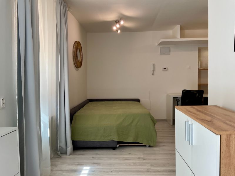Ein Zimmer in einer Einzimmerwohnung mit Bett, Schreibtisch und Schubladen, Boden mit Holzdekor.
