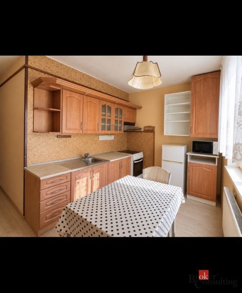 Die Küche in der 2-Zimmer-Wohnung hat einen Boden mit Holzdekor und eine gepunktete Tischdecke.