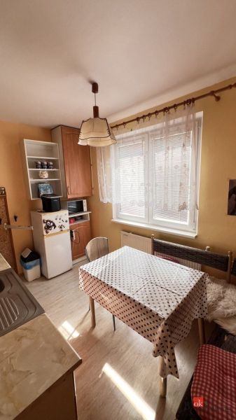 Küche in einer 2-Zimmer-Wohnung mit Esstisch, hohem Schrank und Fenster.