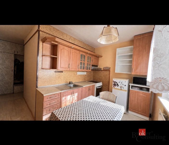 Küche mit Holzelementen, Schränken und Esstisch in einer 2-Zimmer-Wohnung.