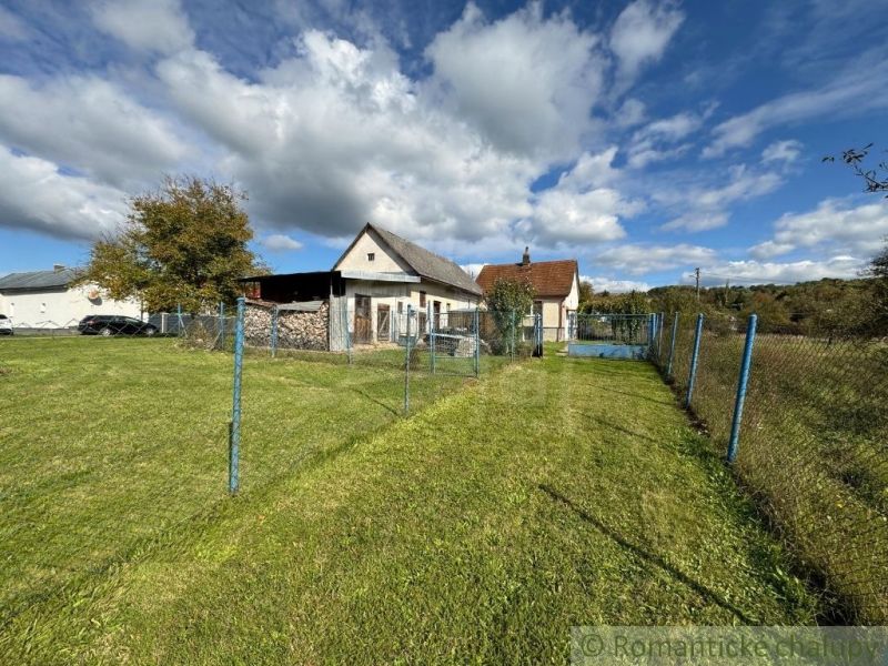 Ein Einfamilienhaus in Volica, umgeben von einem grünen Rasen und einem blauen Zaun unter blauem Himmel.