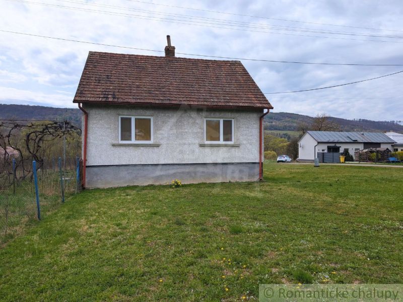 Ein Einfamilienhaus in Volica mit einem grasbewachsenen Grundstück und hügeliger Landschaft im Hintergrund.