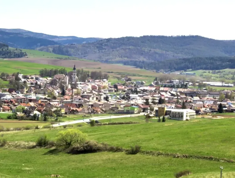 Ľubica, umgeben von landwirtschaftlichen und forstwirtschaftlichen Flächen mit Hügeln im Hintergrund.