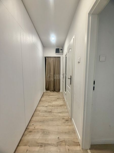 Ein Flur mit weißen Wänden und einem Boden in Holzoptik in einer 3-Zimmer-Wohnung.