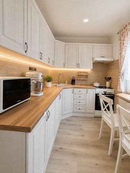 Küche in einer 3-Zimmer-Wohnung mit Holzboden und weißen Möbeln.