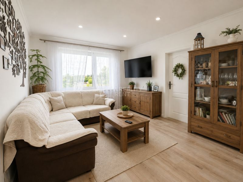 Wohnzimmer in einer 3-Zimmer-Wohnung mit einem bequemen Sofa und einem Boden in Holzoptik.