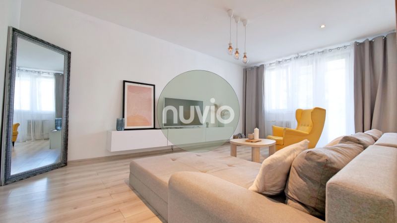 Wohnzimmer mit Sofa, gelbem Sessel und Holzboden in einer 2-Zimmer-Wohnung.