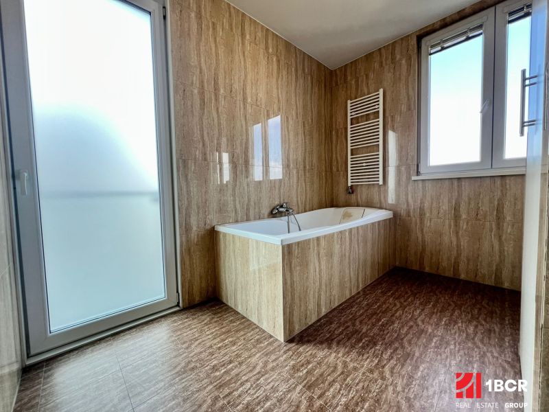 Badezimmer in einer 2-Zimmer-Wohnung mit Badewanne, Fenster und Glastüren.