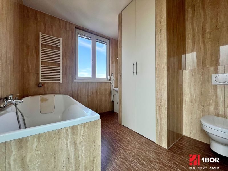 Badezimmer mit Badewanne und Holzboden in einer Zweizimmerwohnung.